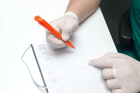 The doctor writes in a notebook at the clinicの写真素材