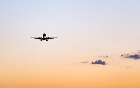 Silhouette of a landing aircraft at sunset