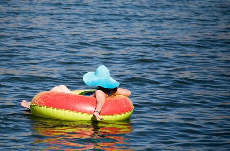 The girl is floating on a tank on the lake