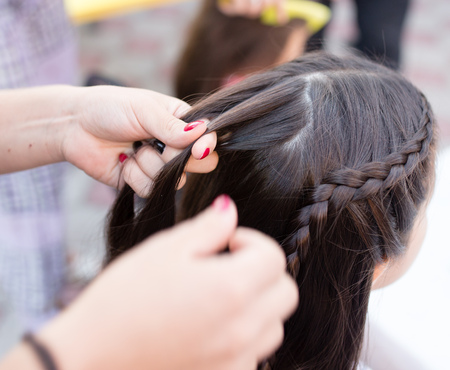 the stylist weaves the female braids on the headの写真素材