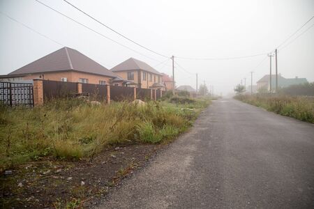 the road in the village in the fog in the morningの写真素材