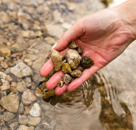 Small stones in the hand on the pond