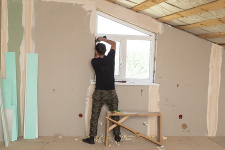 The worker works with plastic for windows in the houseの写真素材