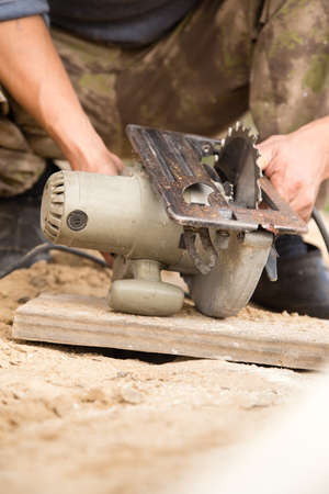 worker saws a wooden plank at a construction siteの写真素材