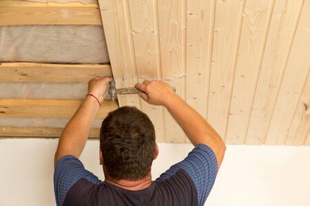 worker working on a wooden ceiling in the houseの写真素材
