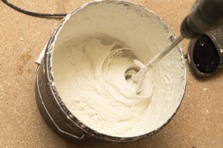 Worker mixes the solution with white plasterの写真素材