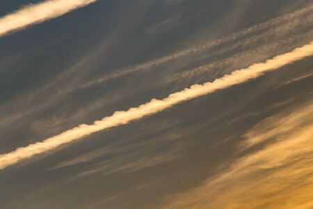trail from the plane in the sky at sunset