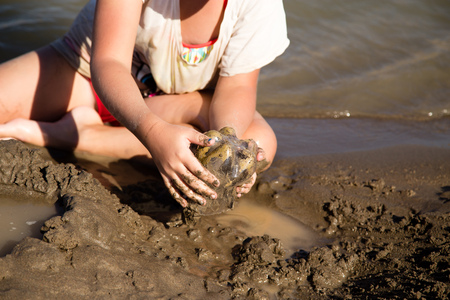 Girl playing in the sand on the lakeの写真素材