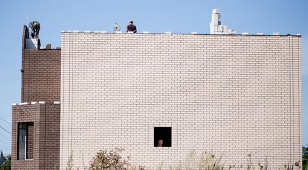 workers work on the roof of a brick house .の写真素材