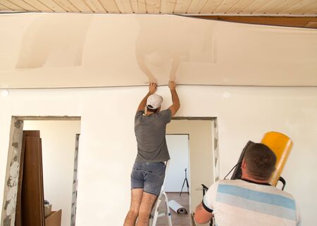 Workers stretch the stretch ceiling in the room .の写真素材