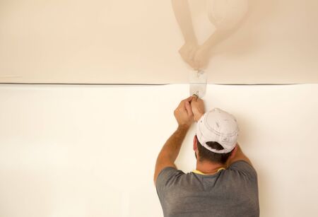 Workers stretch the stretch ceiling in the room .の写真素材