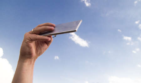 phone in hand on a background of clouds .