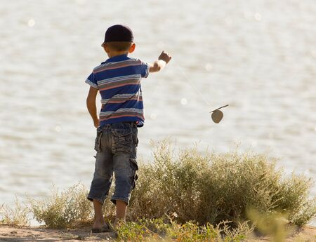 little boy is fishing on the river .の写真素材