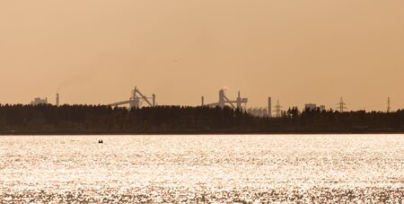 a factory with pipes on the shore of the reservoir .の写真素材