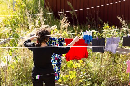 girl hanging clothes on a rope in nature .