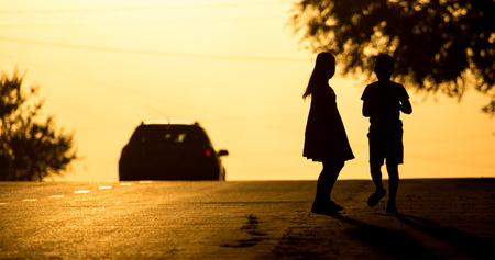 children run across the road at sunset .の写真素材