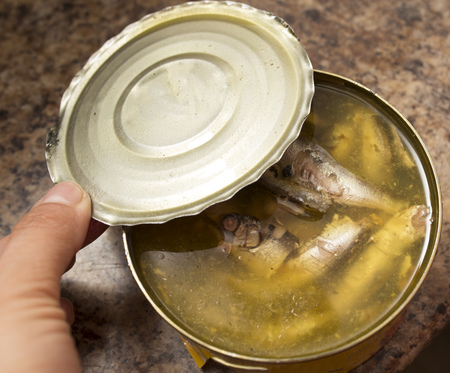 Opens canned fish with a can opener .の写真素材