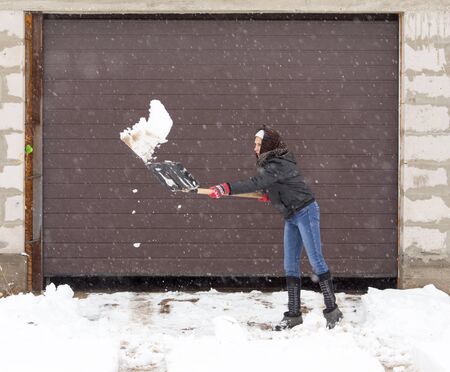 Girl with a shovel cleans the snowの写真素材