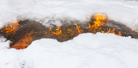 Flame of fire on white snow in winter .の写真素材