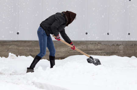 Girl with a shovel cleans the snow .の写真素材