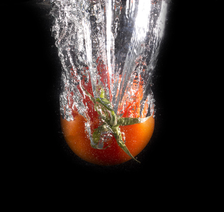 tomato in water on a black background .の写真素材