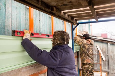 Workers walling the house with wall siding .