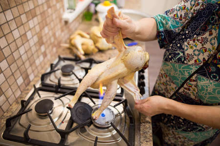 The cook cuts the chicken on fire .の写真素材