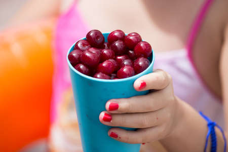 girl with a glass of ripe cherry .