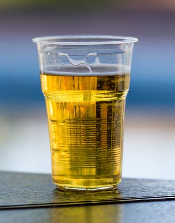 Fresh beer in a plastic glass on the tableの写真素材