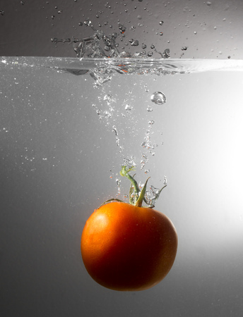 Red tomato drops in water with a spray .の写真素材