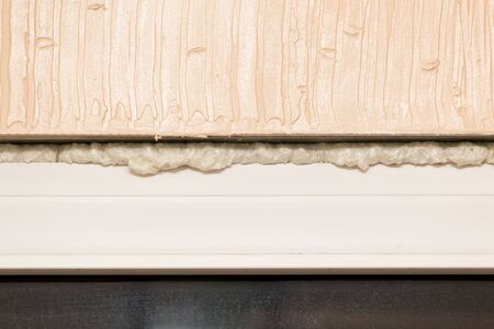Fixing the gap in the door with construction foam .の写真素材