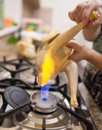 The cook cuts the chicken on fire .の写真素材