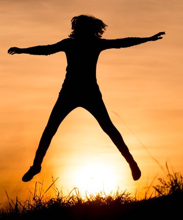 Silhouette of a girl jumping at sunset .の写真素材