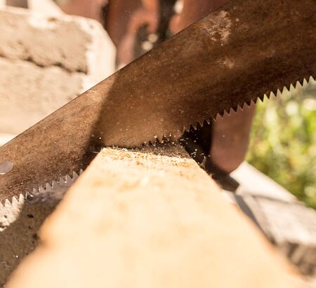 A man is sawing a beam of wood .の写真素材