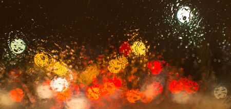 Snow with droplets on the car glass at night .