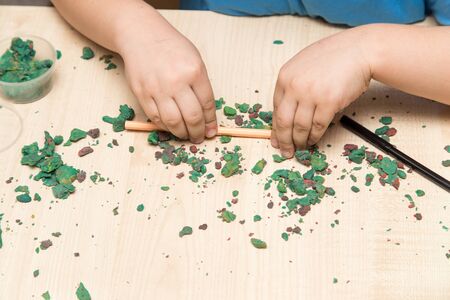 The boy is molding plasticine on the table .の写真素材