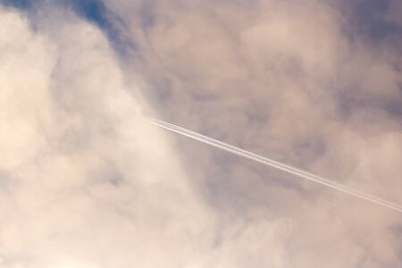 Trail from an airplane in the sky with clouds in the morning .の写真素材
