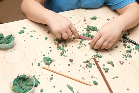 The boy is molding plasticine on the table .の写真素材