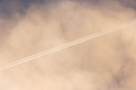 Trail from an airplane in the sky with clouds in the morning .の写真素材