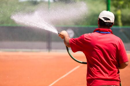 Preparation of a tennis court watering from a hose .の写真素材