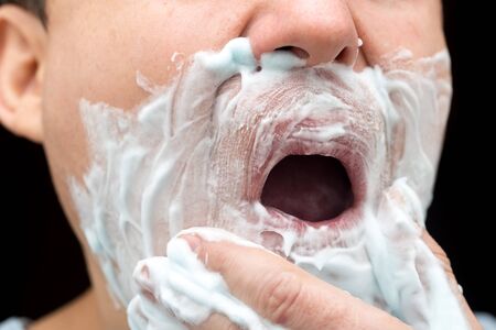 A man is applying face shaving foam .の写真素材