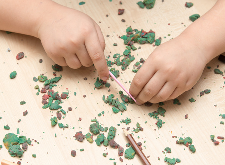 The boy is molding plasticine on the table .の写真素材