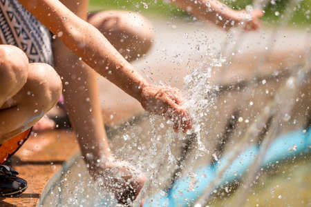 Hand of a girl in a spray of water from a fountain .の写真素材