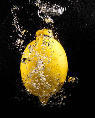 Yellow lemon in water on a black background .の写真素材