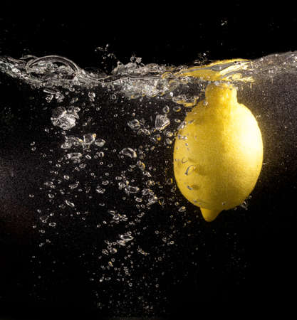 Yellow lemon in water on a black background .の写真素材