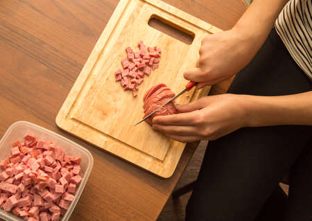 Slicing sausage with a knife on the board .の写真素材