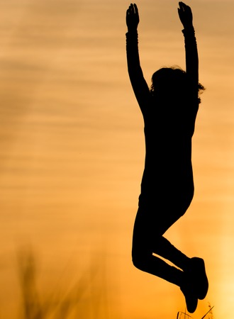 Silhouette of a girl jumping at sunset .の写真素材