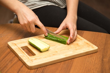 Slicing cucumber with a knife on the boardの写真素材