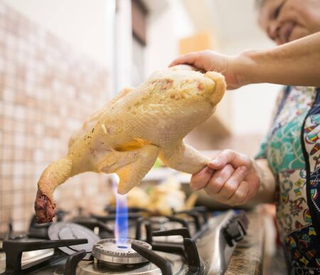 The cook cuts the chicken on fire .の写真素材