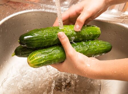 Washing fresh cucumbers in the water under the tap .の写真素材